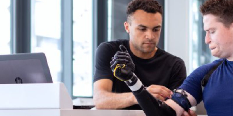 A man with artifical arm sitting next to the computer